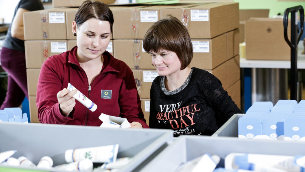 Arbeitsagogin erklärt IV-Mitarbeitenden den Arbeitsablauf beim Ausrüsten