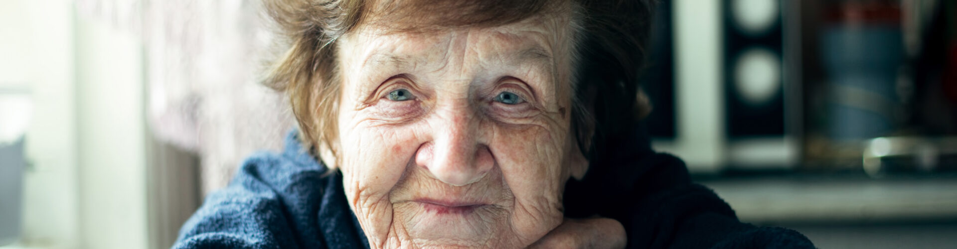 Ältere Frau lächelt und stütz ihr Kinn auf die Arme