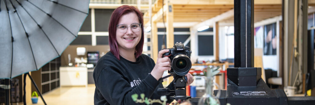 Lernende Fotofachfrau im Fotostudio beim Einrichten der Kamera