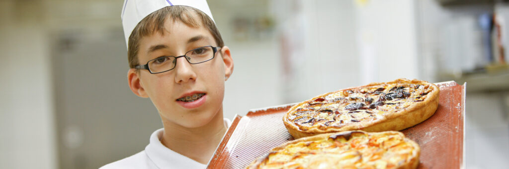 Koch-Lernender mit einem Blech Fruchtfladen