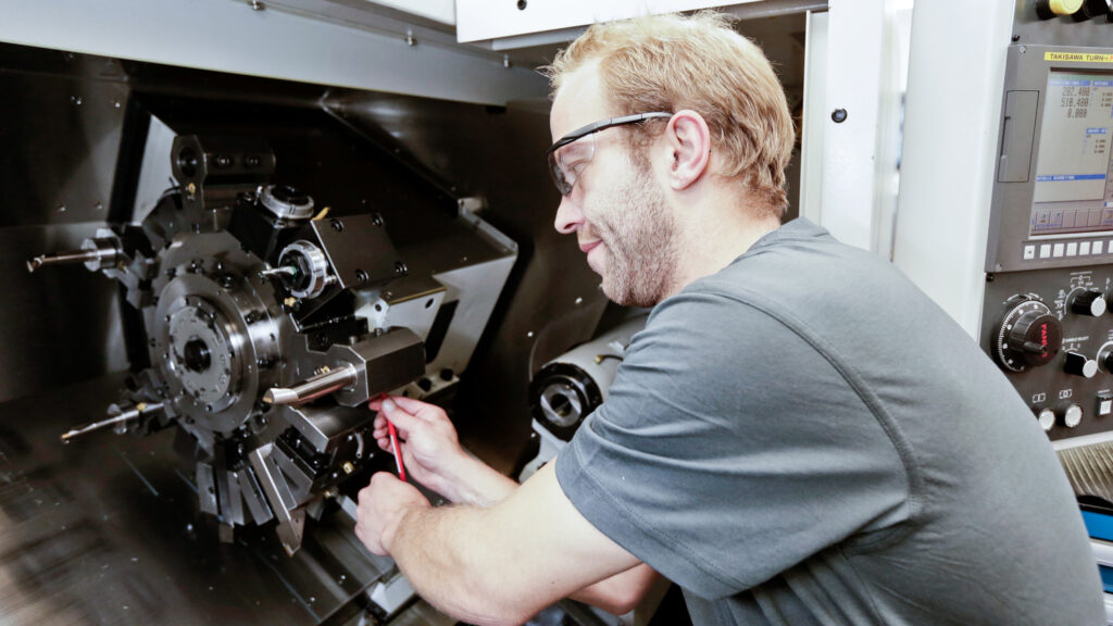 IV-Mitarbeitender bei der Einstellung einer Fräsmaschine