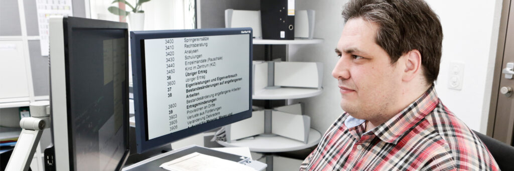 Sehbehinderter Mann am Computer der mit elektronischen Hilfsmitteln ausgestattet ist