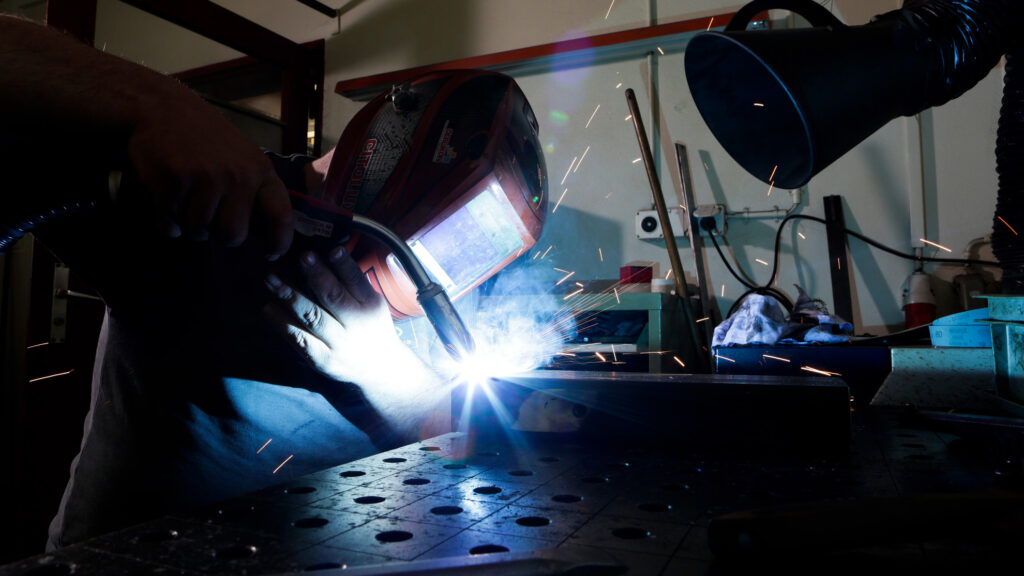 Mann in Schutzmontur beim Schweissen