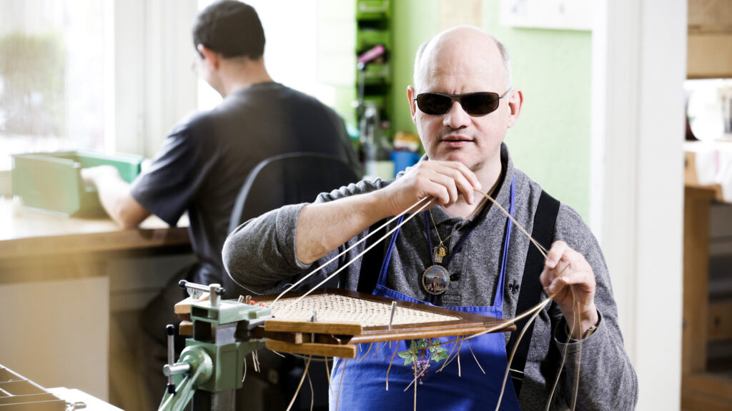 Blinder Mann beim Flechten